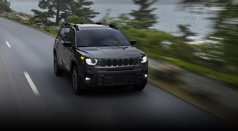 A black 2026 Jeep Cherokee driving to a Jeep dealer near O'neill.