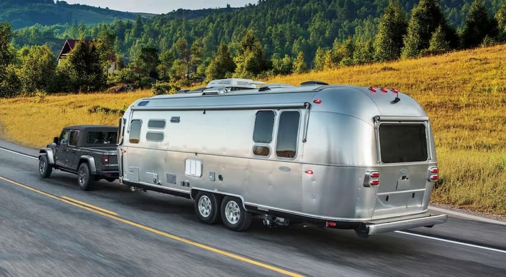 A black 2026 Jeep Gladiator towing a trailer.