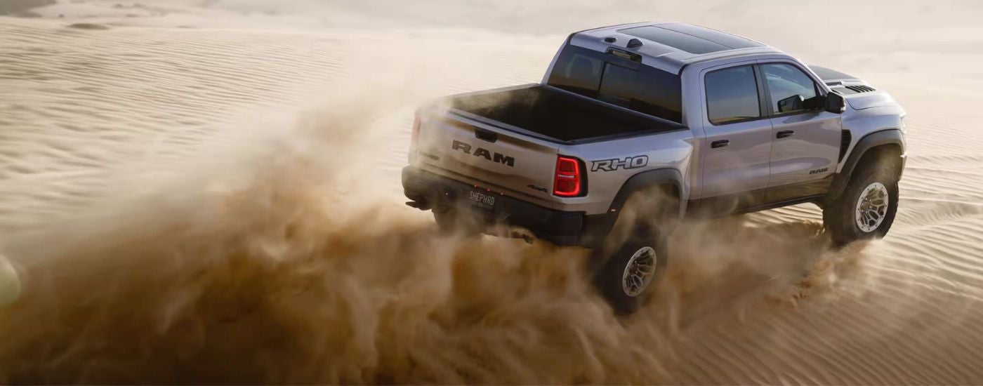 Silver 2026 Ram 1500 RHO kicking up sand driving off-road