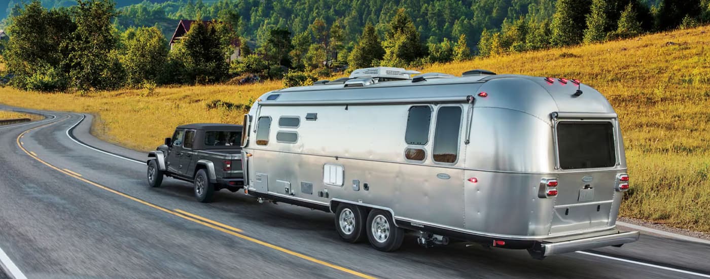 Grey 2026 Jeep Gladiator towing a silver camper trailer