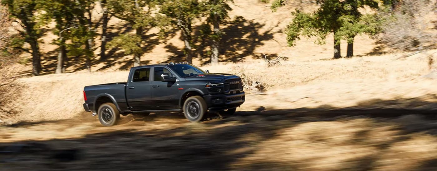 Black 2026 Ram 2500 driving on a dirt road