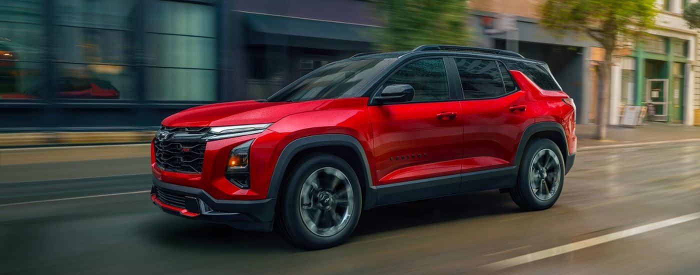 Red 2026 Chevy Equinox driving on a city street.