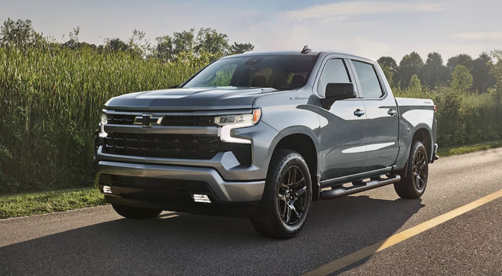 Silver 2027 Chevy Silverado 1500 driving past a field of crops