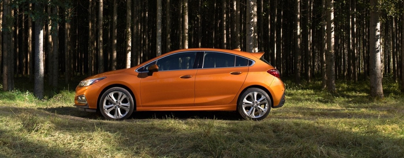 An orange 2017 Chevy Cruze parked in the forest.