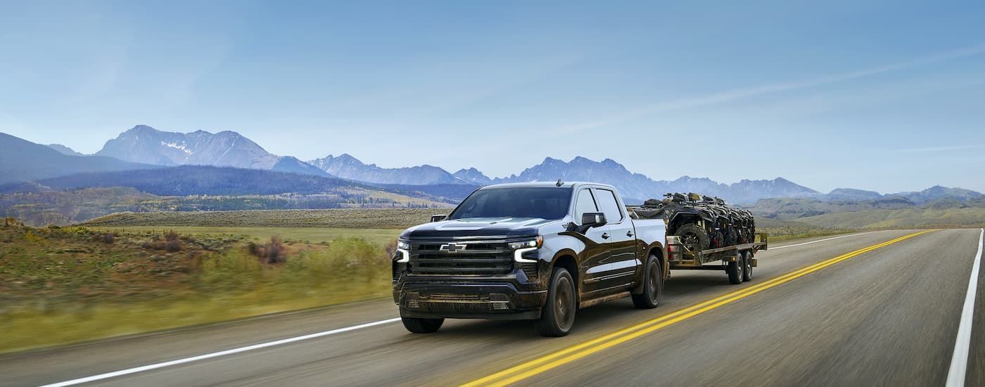 Black 2025 Chevy Silverado 1500 High Country towing a trailer.