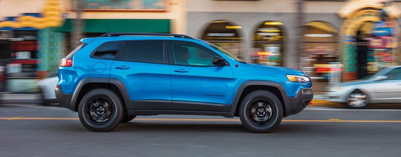 Blue 2023 Jeep Cherokee Trailhawk driving on a city street