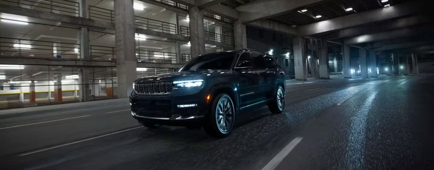 Black 2025 Jeep Grand Cherokee driving to a Jeep dealer