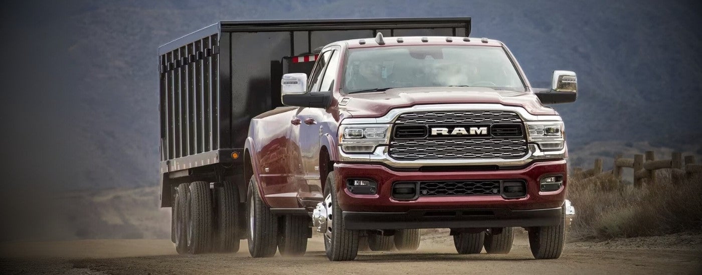 A maroon 2023 Ram 3500 is driving past a fence. A maroon 2023 Ram 3500 is driving past a fence.