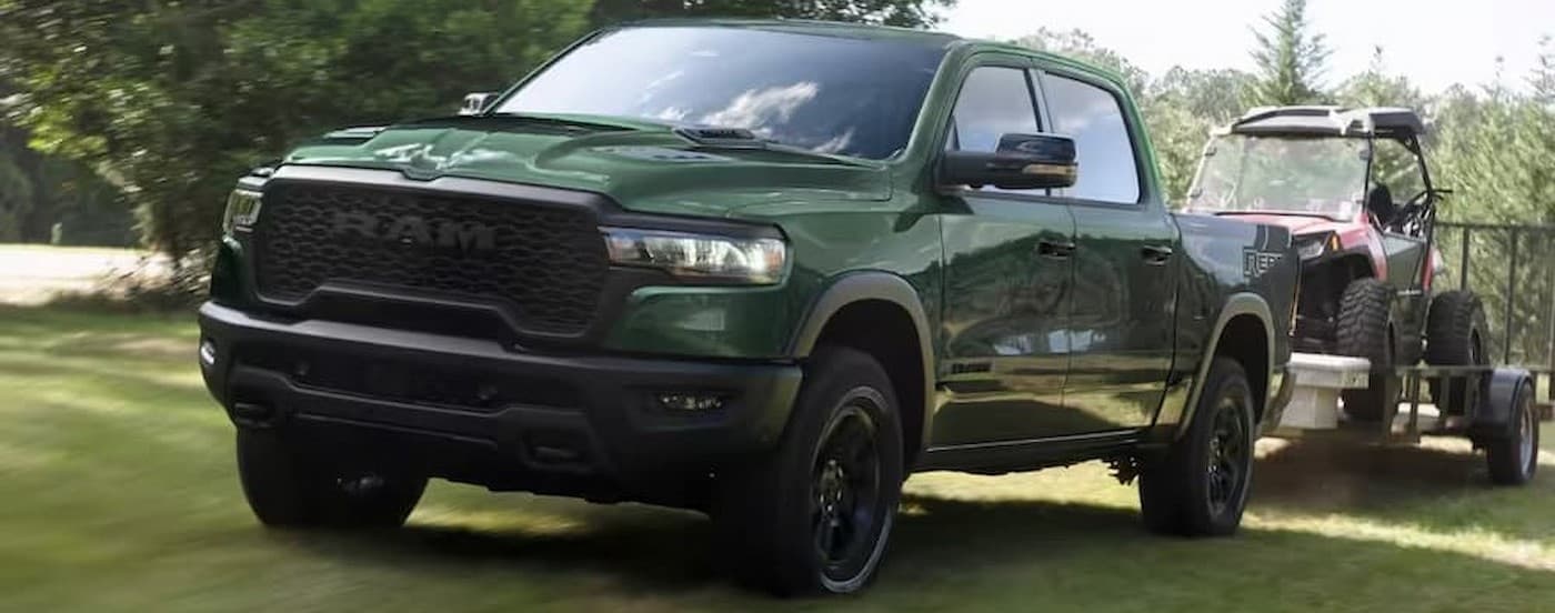 A green 2026 Ram 1500 Rebel towing a trailer.