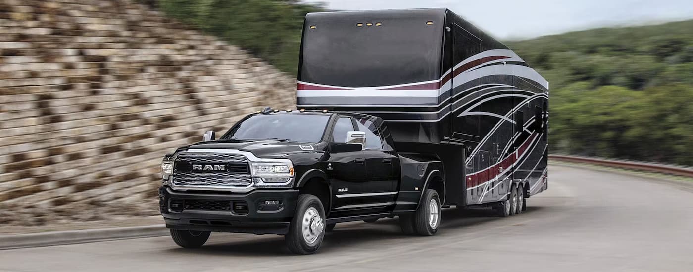 A black 2022 Ram 3500 towing a large camper trailer.