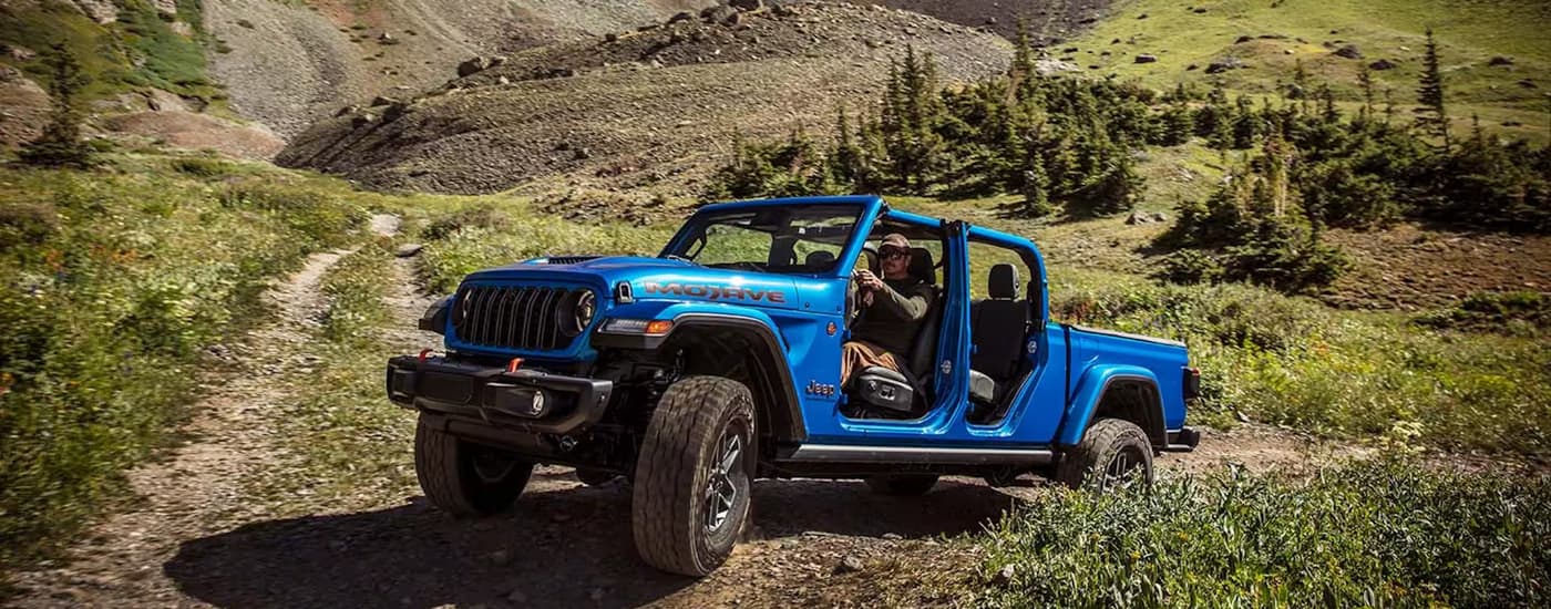 A blue 2026 Jeep Gladiator off-roading on a trail